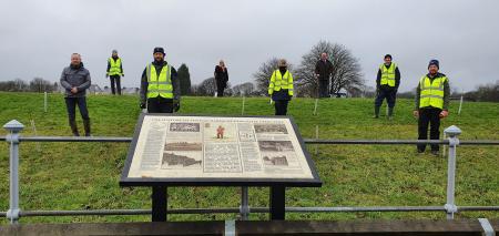 Volunteers standing behind the Fenham Barracks interpretation board at Nunsmoor