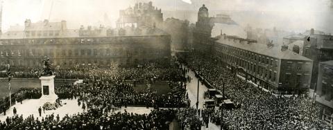 Thousands of people gathered in old Eldon Square and the surrounding area for the unveiling of the War Memorial. Service personnel and veterans can be seen in the crowds. Flowers have been laid at the base of the monument