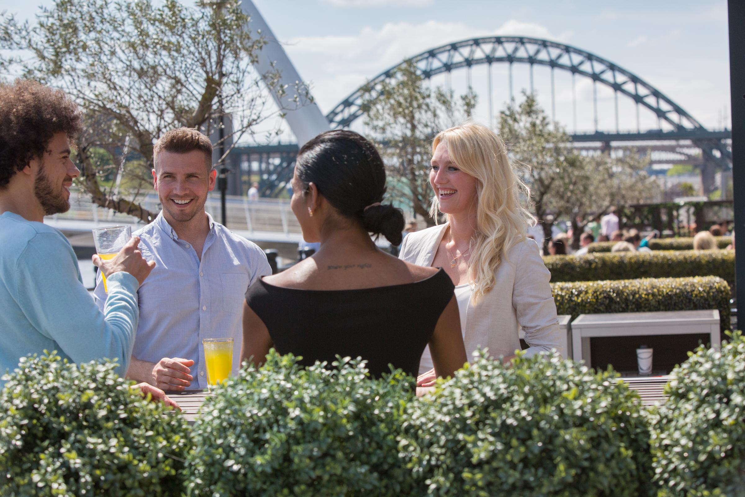 Image of friends sitting in an outside pavement case on the Quayside